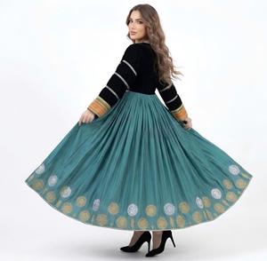 Mujer con un vestido largo plisado en color azul verdoso, con un corpiño de terciopelo negro con adornos tribales de monedas plateadas y un motivo de sol dorado bordado. - Product Image 4