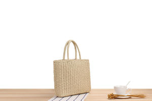 Experimente el lujo silencioso con este hermoso bolso de hilo natural que presenta una forma rectangular estructurada y una textura tejida cálida. - Product Image 2