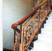 Rampe d'escalier de luxe en or rose avec design floral orné, main courante en bois et marches en marbre pour l'intérieur d'une maison moderne