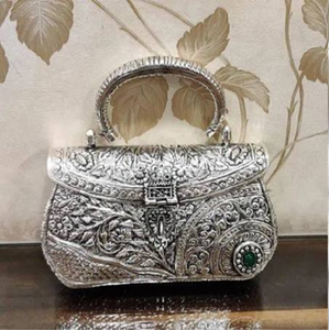Barrel-shaped golden <b>brass</b> hand clutch with detailed floral engraving, a classic lock, and bottom <b>bell</b> charms, at wholesale. - Product Image 4