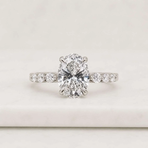 Bague de fiançailles en platine avec diamant ovale taille brillant, sertie de griffes et de diamants latéraux, style classique pour femme - Product Image 1