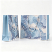Sacs cadeaux imprimés marbre artistique en tons bleus avec message de vœux et poignées en corde torsadée pour marques de luxe de beauté ou de bien-être