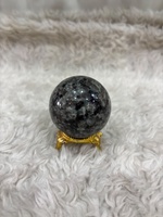 Bola Yooperlite dengan badan batu abu-abu berasap, cahaya fluoresen oranye yang berkilau, kelengkungan yang dipoles, dan tampilan mineral yang khas.