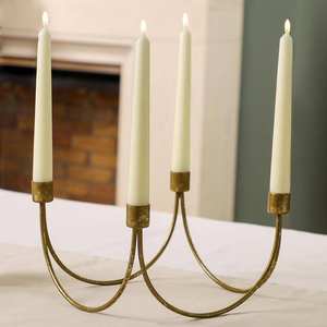 Candelabro de metal dorado con cuatro portavelas cilíndricos y brazo simétrico curvado con elegancia. - Product Image 1