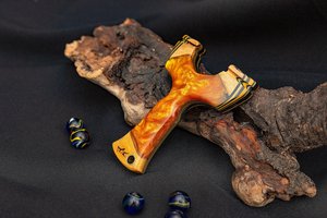 Tirachinas de madera personalizado con acabado efecto llama naranja y detalles negros, diseño ergonómico para uso en exteriores - Product Image 1