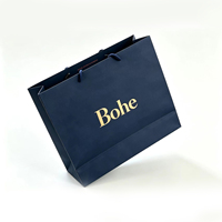 Sac cadeau en papier noir personnalisable de qualité supérieure avec impression de logo doré métallique et poignées en ruban plat pour l'emballage de produits de luxe