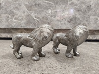 Statues de lions majestueux en métal (lot de 2) : avec de larges crinières et une posture robuste et agressive, ces sculptures argentées symbolisent la force.