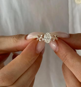 Anillo de compromiso de diamante blanco de corte ovalado en oro rosa macizo con banda floral de hojas y diamantes marquesa, diseño clásico de tallos y engaste de puntas finas. - Product Image 1