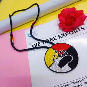 Collier artisanal avec pendentif patte d'ours perlé, sections jaunes, rouges, blanches et noires, et cordon long à suspendre sous la poitrine - Product Image 2