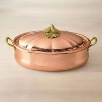 Casserole ovale en cuivre poli avec couvercle décoratif en forme d'oiseau doré et poignées latérales dorées, ustensile de cuisine de luxe pour servir et presenter.