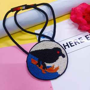 Collier pendentif oiseau noir perlé fait main, design circulaire avec détails bleus, blancs et oranges, pour un usage artistique et culturel - Product Image 1