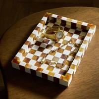 Bandeja rectangular a cuadros para servir con reloj y cadena dorados sobre mesa de madera
