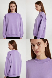 Joven mujer elegante en una sudadera extragrande de cuello redondo en color blanco puro, con un ajuste relajado y tela suave, posándose de manera informal en un estudio luminoso. - Product Image 3
