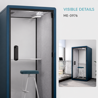Cabine téléphonique de bureau moderne et compacte bleue avec porte en verre, étagère intérieure, tabouret blanc et espace de travail privé