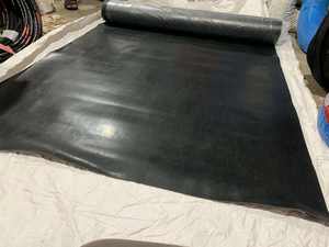 Feuille de caoutchouc industrielle roulée sur table de travail métallique dans une atelier moderne avec étagères à outils et environnement de fabrication - Product Image 2