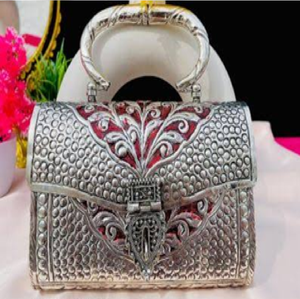 Barrel-shaped golden <b>brass</b> hand clutch with detailed floral engraving, a classic lock, and bottom <b>bell</b> charms, at wholesale. - Product Image 3
