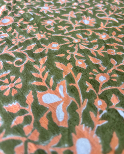 Tela de algodón estampada a mano en India con diseño floral en tonos melocotón y azul sobre base verde oliva - Product Image 1