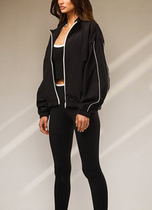 Chaqueta cortavientos negra personalizada al por mayor con logo, para mujer, con cremallera completa, cuello tipo embudo y ribetes en contraste, tela con ligeras arrugas. - Product Image 3