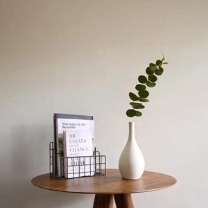 Jarrón minimalista de cerámica blanca con rama de eucalipto sobre mesa de madera - Product Image 1
