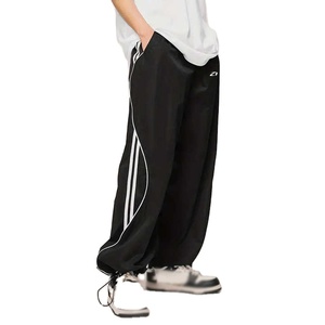 กางเกงแทร็คขายาวสีดำทรงหลวมสำหรับผู้ชาย ผ้าไนลอนน้ำหนักเบา แต่งแถบสีตัดกัน สไตล์สตรีทแวร์ ทรงสบาย รับผลิตตามสั่ง - Product Image 1