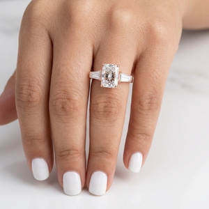 Anillo de compromiso personalizado con tres diamantes radiantes y piedras laterales cónicas tipo baguette. - Product Image 1