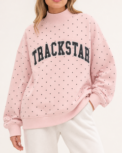 เสื้อสเวตเชิ้ตคอเต่าลายจุดสีชมพูบลัช ตราสัญลักษณ์ Trackstar พร้อมตัวอักษรสีดำขอบสีขาว แขนยาวแบบเรียบ - Product Image 1