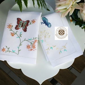 Delicada mariposa junto a flores en pleno floración bordadas en servilletas de lino, que aportan un suave encanto de jardín a las mesas de comedor elegantes. - Product Image 1