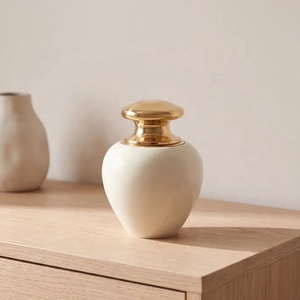 Urna Moderna de Metal Color Marfil con Tapa Dorada Esculpida, Cuerpo Curvo Liso y Diseño Compacto para Homenaje Conmemorativo - Product Image 2