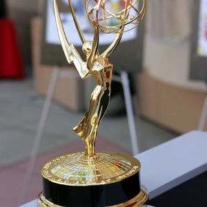 Figura icónica dorada con alas sosteniendo una esfera atómica. Disponible a precios de mayorista. - Product Image 1