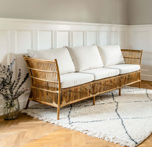 Handcrafted <b>bamboo</b> rattan three-seater couch featuring soft beige fabric cushions, available at wholesale prices. - Product Image 1