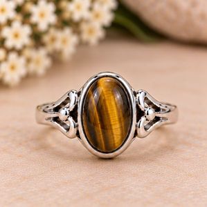 Bague élégante en argent avec pierre œil de tigre ovale, surface de pierre précieuse brillante aux couleurs marron miel chaud et détails latéraux sculptés avec raffinement. - Product Image 4