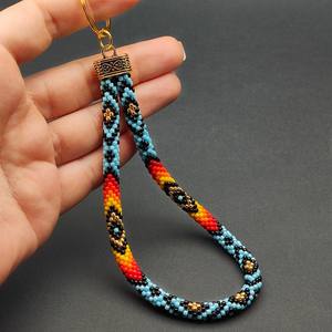 Llavero de muñeca artesanal con cuentas para mujer, moderno, con patrón de diamantes en azul, rojo, amarillo, negro y dorado, y soporte decorativo para anillo dorado. - Product Image 1