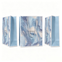 Sacs cadeaux imprimés marbre artistique en tons bleus avec message de vœux et poignées en corde torsadée pour marques de luxe de beauté ou de bien-être