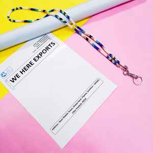 สร้อยประดับร่างกายทำมือหลากสีสันที่สวมใส่โดยผู้หญิงที่สวมเสื้อสีขาวและมีบัตรประจำตัวที่มองเห็นได้ แสดงถึงงานฝีมือของช่างฝีมืออย่างภาคภูมิใจ - Product Image 3