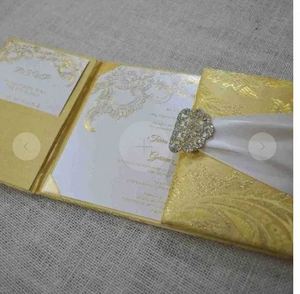 การ์ดเชิญงานแต่งงานผ้าไหมโบรเคดสีทองคุณภาพสูง พร้อมริบบิ้นสีงาช้างและเข็มกลัดคริสตัล ราคาดีที่สุดจากซัพพลายเออร์การ์ดแต่งงาน - Product Image 1