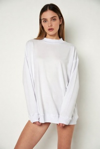 Joven mujer elegante en una sudadera extragrande de cuello redondo en color blanco puro, con un ajuste relajado y tela suave, posándose de manera informal en un estudio luminoso. - Product Image 1