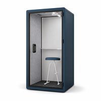 Cabine téléphonique de bureau moderne et compacte bleue avec porte en verre, étagère intérieure, tabouret blanc et espace de travail privé