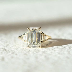 Elegant <b>Emerald</b> Cut Lab Grown Diamond <b>Ring</b> With Tapered Side Stones And Luxurious Gold Band Design - Product Image 1