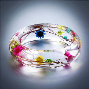 Clear resin bangle with intertwined natural <b>twigs</b> and colorful dried wildflowers, available at wholesale prices. - Product Image 1