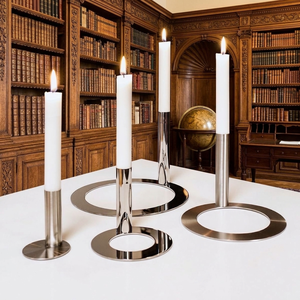 Juego de portavelas modernos de cromo pulido con elegantes anillos de base redonda entrelazados, tallos delgados y velas cónicas blancas altas. - Product Image 1