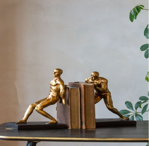 Sujetalibros de metal con figuras humanas dinámicas que parecen empujar libros, disponibles a precios de mayorista para exhibiciones creativas y activas en estanterías. - Product Image 1