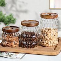 Pot en verre à finition lisse avec couvercle en bois pour un rangement élégant et un nettoyage facile, avec un verre robuste et un couvercle en bois.