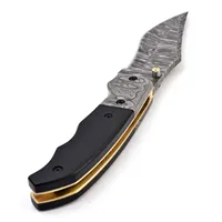 Couteau pliant à manche sculpté noir avec lame à motifs, poignées argentées et garnitures dorées, idéal pour le camping et la collection