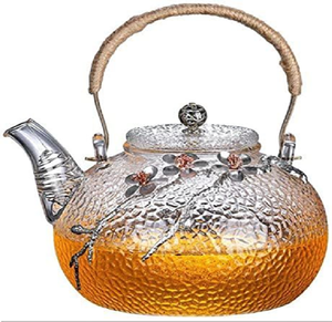 Tetera de vidrio martillado y metal con detalles florales y un asa de cuerda rústica. Artículo único disponible a precios de mayorista. - Product Image 1