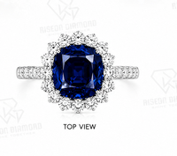 Magnifique bague halo en or blanc 18 carats avec pierre centrale bleu roi taille coussin, halo de diamants ronds et sangle fendue pavée brillante.