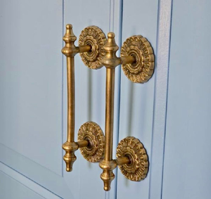 Paire de poignées rustiques dorées avec supports circulaires décoratifs sur une porte bleue, disponibles à prix de gros. - Product Image 1