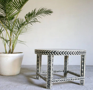 Elegante taburete redondo con incrustaciones de hueso, con un patrón geométrico de chevron en blanco y negro, disponible a precios de mayorista. - Product Image 1