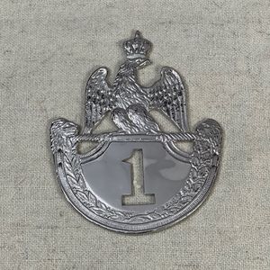 Cette pièce de collection vintage est une plaque shako argentée, ornée d'un aigle couronné sur un emblème numéro 1. - Product Image 1