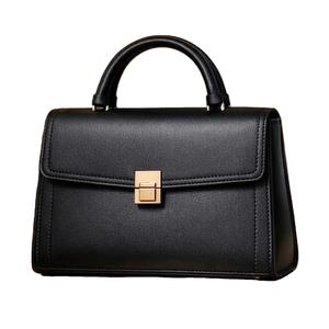 Ce sac à main en cuir noir avec une poignée supérieure et un fermoir doré est similaire aux sacs à rabat proposés par les détaillants. - Product Image 1