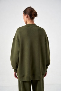 Joven mujer elegante en una sudadera extragrande de cuello redondo en color blanco puro, con un ajuste relajado y tela suave, posándose de manera informal en un estudio luminoso. - Product Image 4